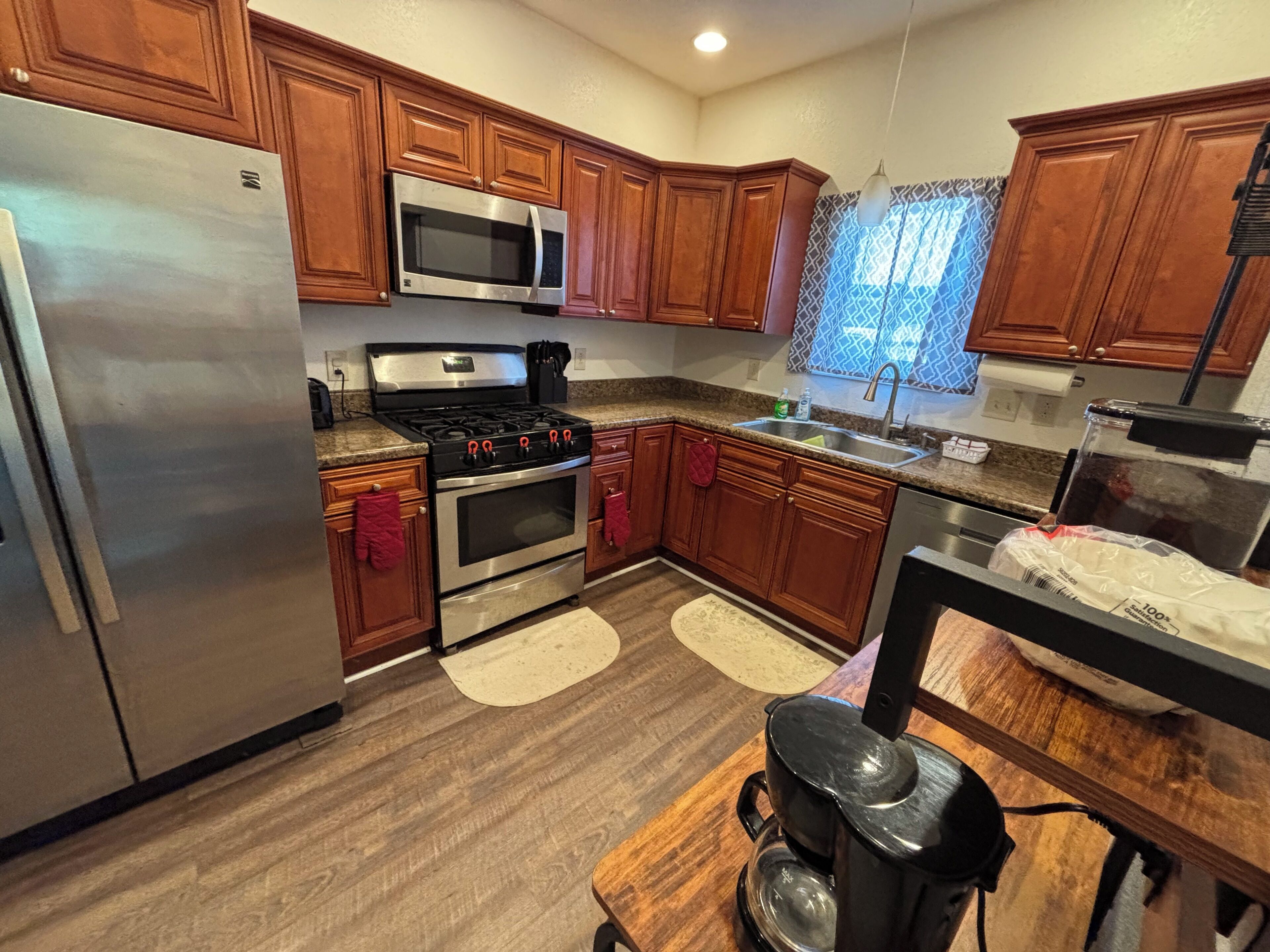 A kitchen with wooden cabinets, stainless steel appliances, a microwave, stove, oven, and a coffee maker.