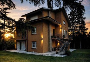 A two-story building with a balcony, a staircase, and a well-maintained lawn. - Charming Villa with a Hot Tub in a Pine Forest (Talacchio)