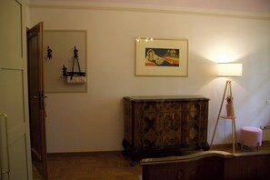Een kamer met een houten kast, een lijst met een afbeelding aan de muur, een lamp en een deur.