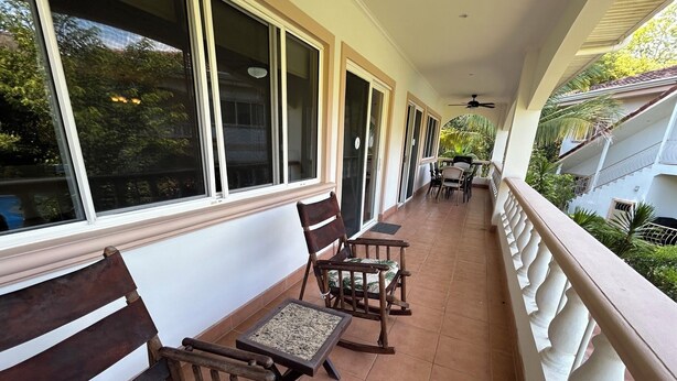 A covered balcony with wooden benches and a table, surrounded by windows and a white railing. - Luxury 2nd Floor Condo - 5 Minute Walk to Award-Winning Playa Hermosa Beach (Playa Hermosa)