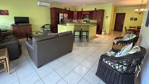 A living room with a sofa, a television, and a dining area with chairs and a table. - Luxury 2nd Floor Condo - 5 Minute Walk to Award-Winning Playa Hermosa Beach (Playa Hermosa)