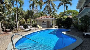 A swimming pool with a tiled deck, surrounded by palm trees and lounge chairs. - Luxury 2nd Floor Condo - 5 Minute Walk to Award-Winning Playa Hermosa Beach (Playa Hermosa)