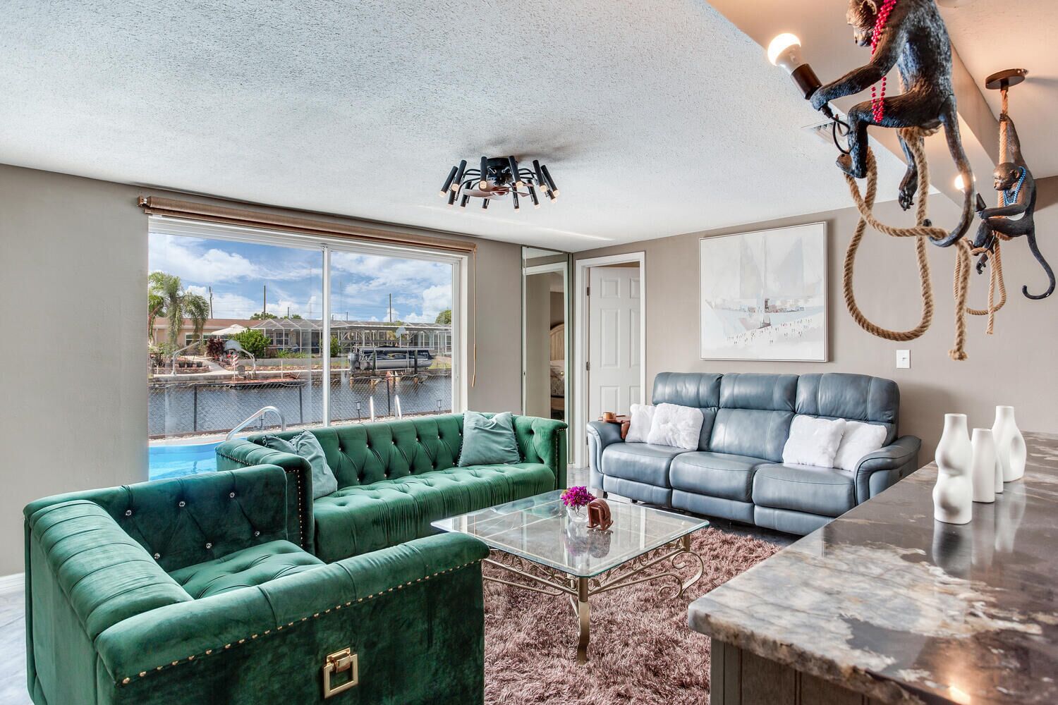A living room with a green sofa, a blue leather couch, and a glass coffee table.