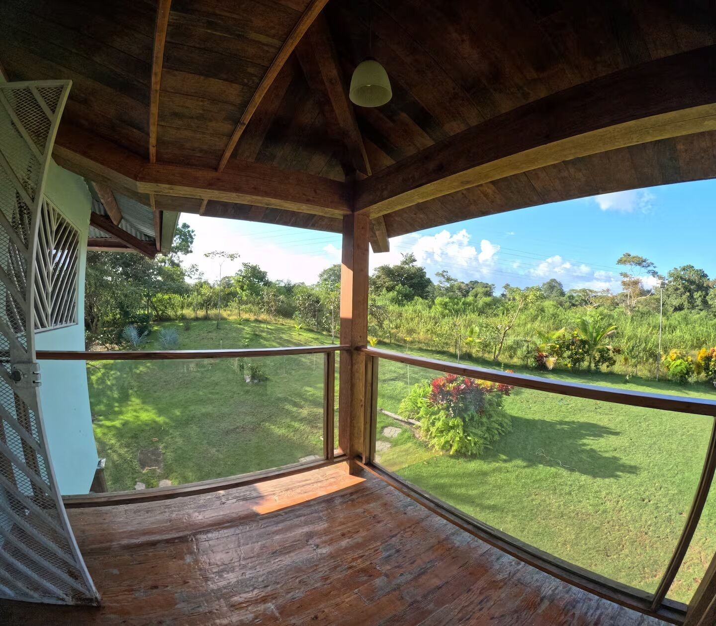 Una terraza de madera con vistas a un jardín exuberante y árboles.