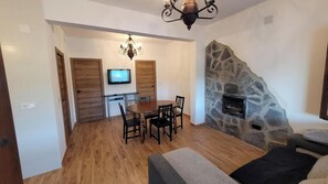 A dining area with a wooden table and chairs, a television mounted on the wall, and a stone fireplace. - Finca 3R Vélez-Málaga by Ruralidays (Málaga)