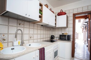A kitchen with white cabinets, a double sink, a microwave, and a stove. - VILLA 200 METERS FROM THE BEACH, GARDEN WITH GAZEBO AND BARBECUE AREA, PARKING SPACE INCLUDED (San Vito Lo Capo)