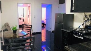 Una cocina con refrigerador negro, estufa y comedor con mesa y sillas.