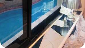 Una habitación con vistas a una piscina, una lámpara y una cortina estampada.
