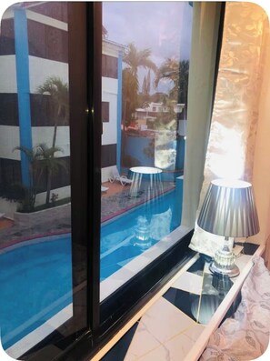 Ein Zimmer mit Blick auf einen Swimmingpool, einer Lampe und einem Vorhang mit Muster.