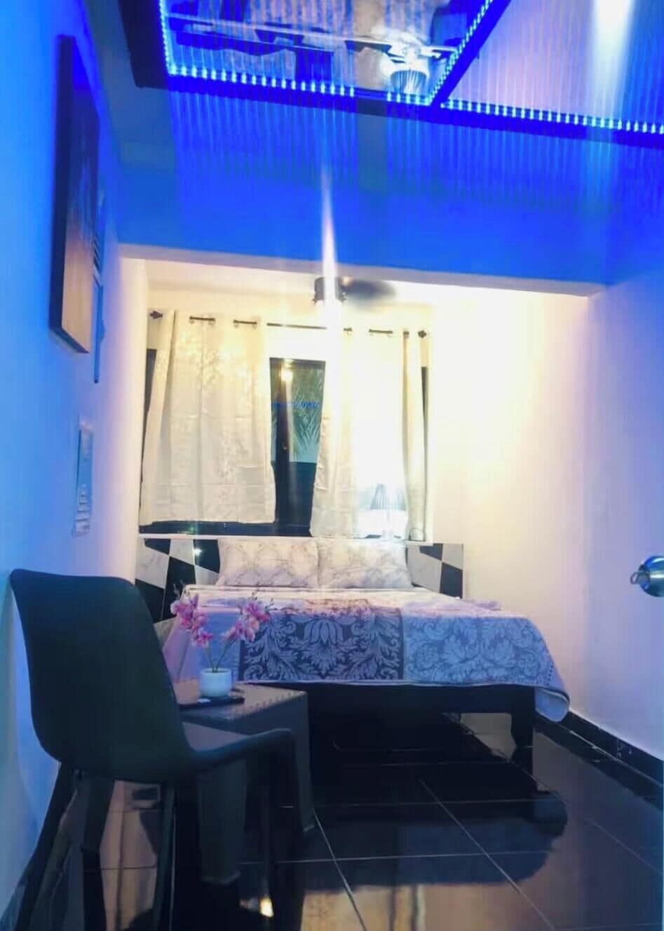 Un dormitorio con cama, una silla, un escritorio y un ventilador de techo.