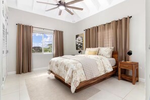 A bedroom with a large bed, a ceiling fan, a nightstand, and a window with curtains. - Richmond Estate 3rd floor condo~ Pool~Beach Access (Claremont)