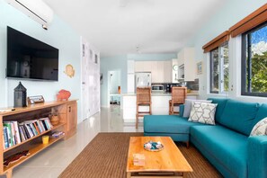 A modern living room with a teal sofa, a coffee table, and a bookshelf. - Teal Horizon~OceanfrontCaribbeanEscape - Tower Isle (Tower Isle)