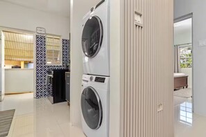 Eine moderne Küche mit eingebauter Waschmaschine und Trockner, einer gemusterten Spritzschutzleiste und Blick auf das angrenzende Schlafzimmer.