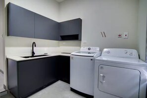 Uma cozinha compacta com pia, armários escuros e máquina de lavar e secar frontais.
