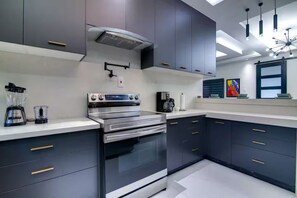 Uma cozinha moderna com armários escuros, eletrodomésticos de aço inoxidável e bancada branca.