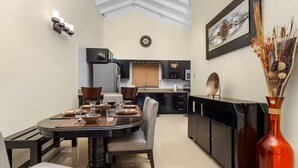A modern kitchen with a dining area, featuring a round table set for four, a black cabinet, and a decorative vase. - 3BR Oasis in Drax hall ~ Pool~ Gym ~ Gated ~Tennis (Saint Ann's Bay)
