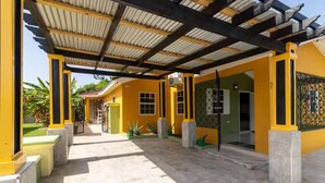 A covered outdoor area with a tiled floor, yellow walls, and a metal roof structure. - 3BR Oasis in Drax hall ~ Pool~ Gym ~ Gated ~Tennis (Saint Ann's Bay)