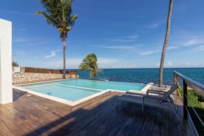 A wooden deck with a pool and lounge chairs overlooking the ocean. - Blue Serenity ~ Oceanfront Penthouse ~Tower Isle (Tower Isle)