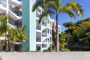 A multi-story building with balconies, palm trees, and a clear blue sky. - Blue Serenity ~ Oceanfront Penthouse ~Tower Isle (Tower Isle)