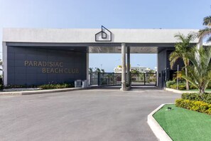A gated entrance to Paradisiac Beach Club with a modern design and a clear sky. - The Vue @ Paradisiac ~ Private Beach ~ Pool ~Gated (St. Ann Parish)