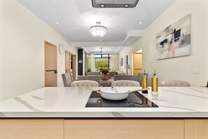 A modern dining area with a marble countertop, a chandelier, and a view of the outdoors.