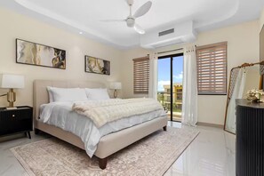 A bedroom with a bed, nightstands, a ceiling fan, artwork, and a view through the window. - The Vue @ Paradisiac ~ Private Beach ~ Pool ~Gated (St. Ann Parish)