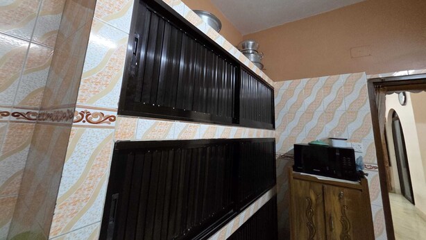Una cucina con un forno a microonde, un lavandino e un armadietto.