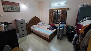 Una camera da letto con un letto, una scrivania, un armadio, una ventola a soffitto, una finestra con tende e una lampada a parete.
