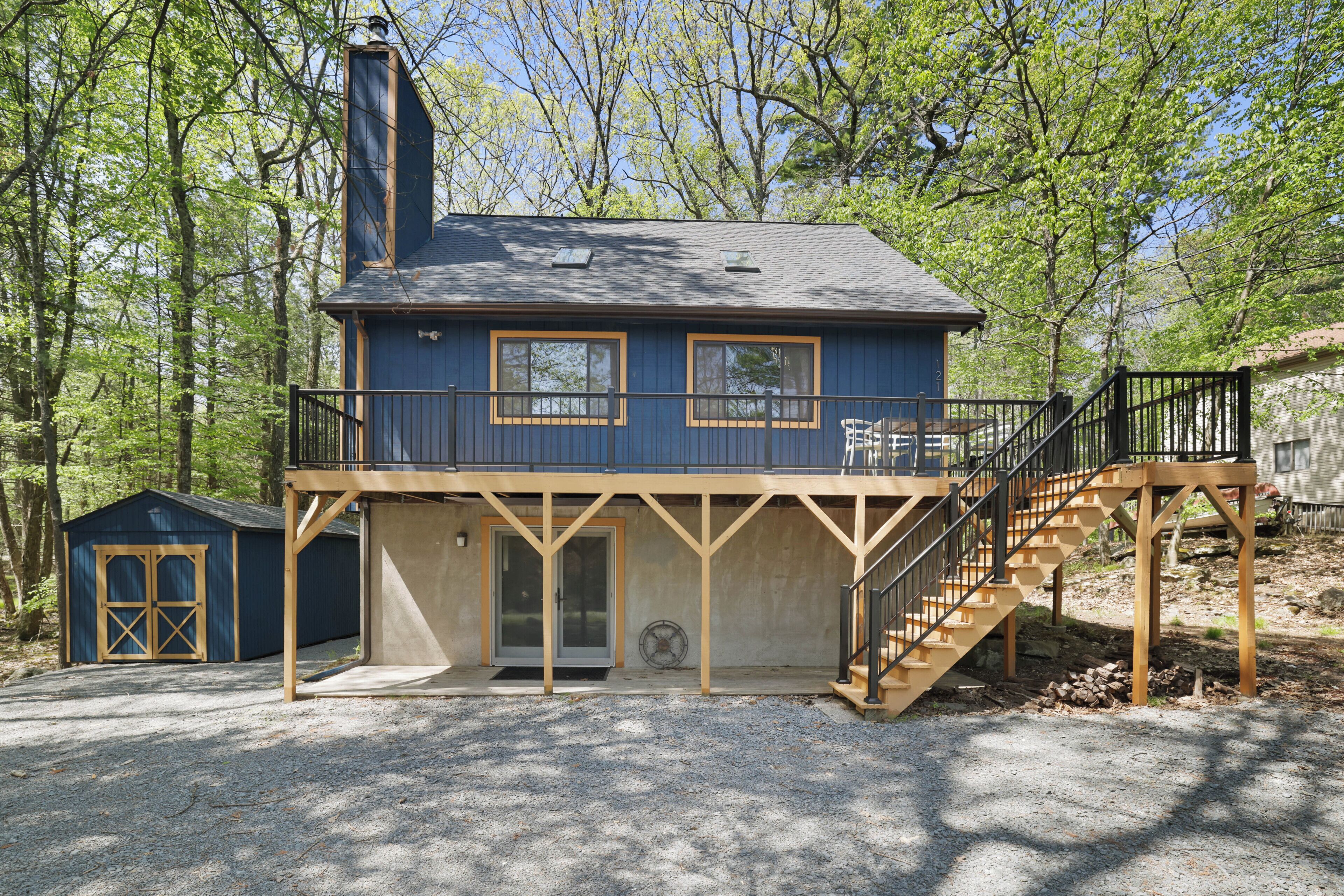 A two-story building with a balcony, a staircase, and a small shed.
