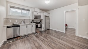 Una cocina moderna con armarios blancos, electrodomésticos de acero inoxidable y piso de madera.