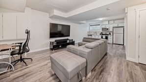 Una sala moderna con un sofá modular, un televisor y un comedor con mesa y sillas.