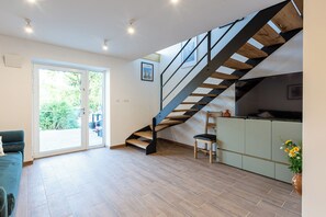 Et moderne interiør med trappe, spiseplads og udsigt gennem en glasdør.