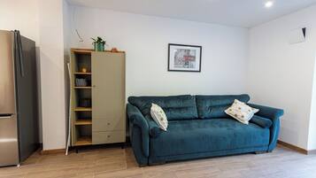 A modern living room with a teal sofa, a built-in wardrobe, and a framed picture on the wall.