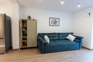 En moderne stue med en turkis sofa, en indbygget garderobe og et billede i ramme på væggen.