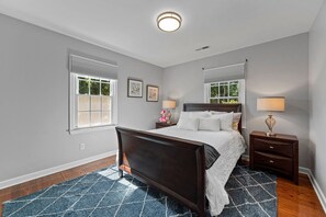 A bedroom with a bed, bedside tables, a window, and a ceiling light fixture.