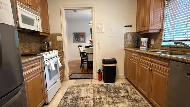 A kitchen with wooden cabinets, a stainless steel refrigerator, a microwave, and a stove. - Rio Vista Gem , Walk to Las Olas , 6 Min to Beach ,Private Backyard 2 Bedrooms (Fort Lauderdale)