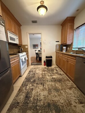 A kitchen with wooden cabinets, a stainless steel refrigerator, a microwave, and a stove. - Rio Vista Gem , Walk to Las Olas , 6 Min to Beach ,Private Backyard 2 Bedrooms (Fort Lauderdale)