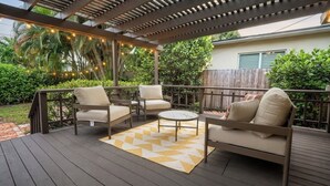 An outdoor patio with a wooden deck, two sofas, a round coffee table, and a patterned rug. - Rio Vista Gem , Walk to Las Olas , 6 Min to Beach ,Private Backyard 2 Bedrooms (Fort Lauderdale)