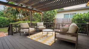 Eine Terrasse im Freien mit Holzdeck, zwei Sofas, einem runden Couchtisch und einem gemusterten Teppich.