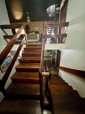 A wooden staircase with a handrail, leading to a landing with a bed and a chair. - Beach house with pool in Porto das Dunas, 7 bedrooms + garage for 6 cars. (Aquiraz)