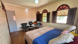 A bedroom with a bed, a chair, a fan, and a window with shutters. - Beach house with pool in Porto das Dunas, 7 bedrooms + garage for 6 cars. (Aquiraz)