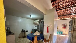A kitchen with a dining table, chairs, a refrigerator, and a tiled floor. - Beach house with pool in Porto das Dunas, 7 bedrooms + garage for 6 cars. (Aquiraz)