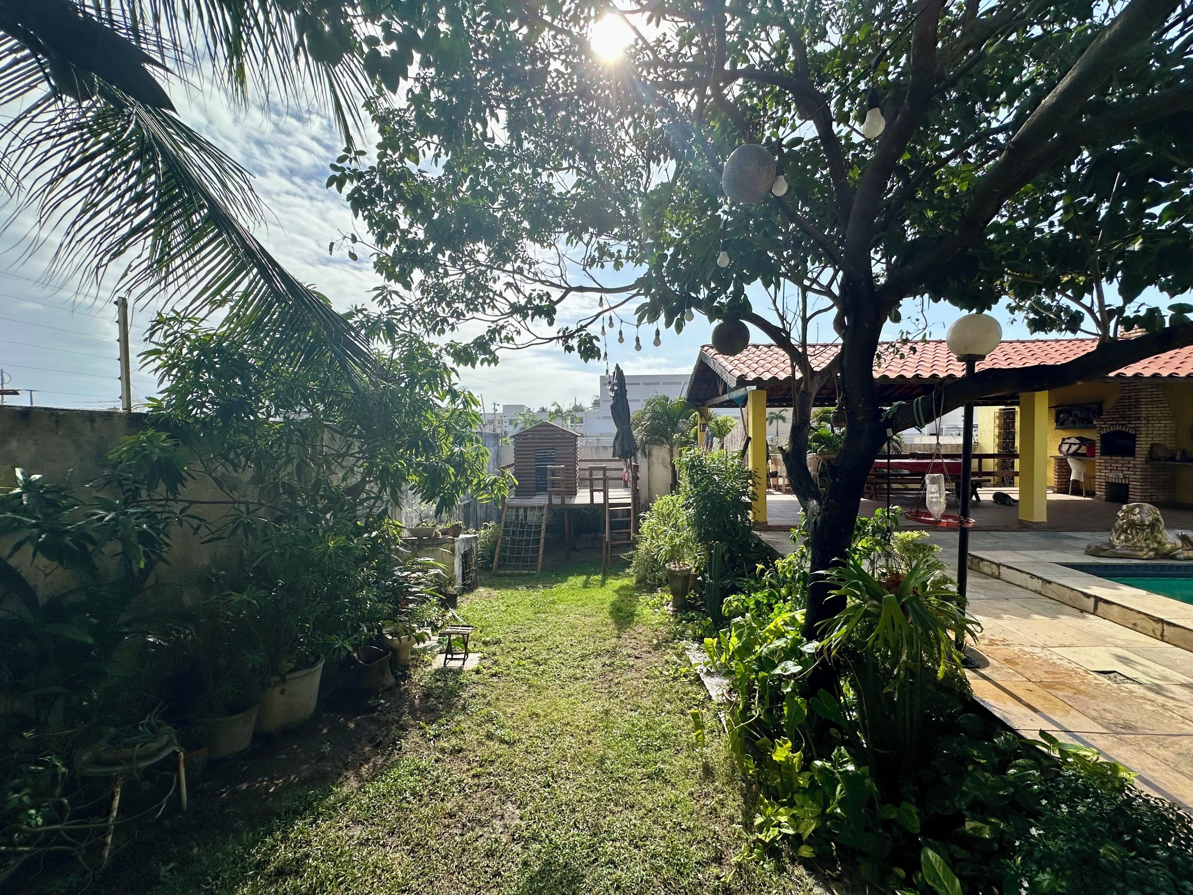 Ein Garten mit Terrasse, Pool und einem Backofen aus Ziegeln.