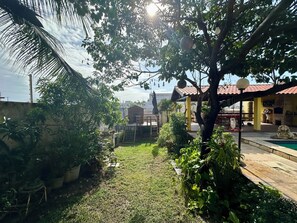 Ein Garten mit Terrasse, Pool und einem Backofen aus Ziegeln.