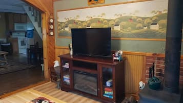 A living room with a television on a wooden cabinet, a fireplace, and a mural on the wall.