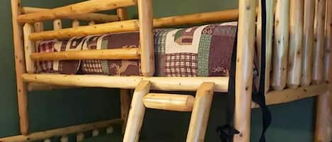 Un letto a castello con una scala, una coperta e una parete verde.