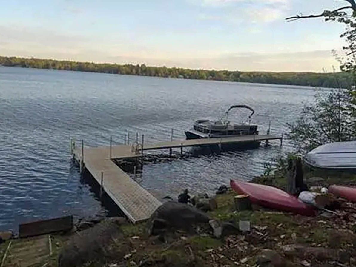 A lake with a dock extending into the water, surrounded by trees.