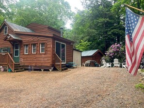 A rustic cabin with a porch, a flag, and outdoor seating.