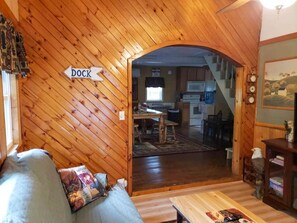 A wooden interior with a couch, a table, and a sign indicating a dock. - Cozy Adirondack Woodland Retreat- near Caroga Lake (Caroga Lake)
