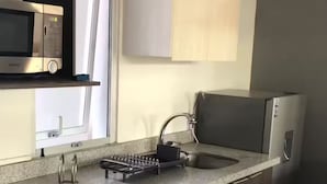 Une cuisine équipée d’un four à micro-ondes encastré, d’un évier avec un robinet et d’un plan de travail muni d’un égouttoir à vaisselle.